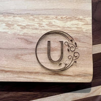Detail image of the monogrammed board with an U engraved into the bottom right