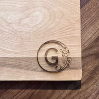 Detail image of the monogrammed board with an G engraved into the bottom right